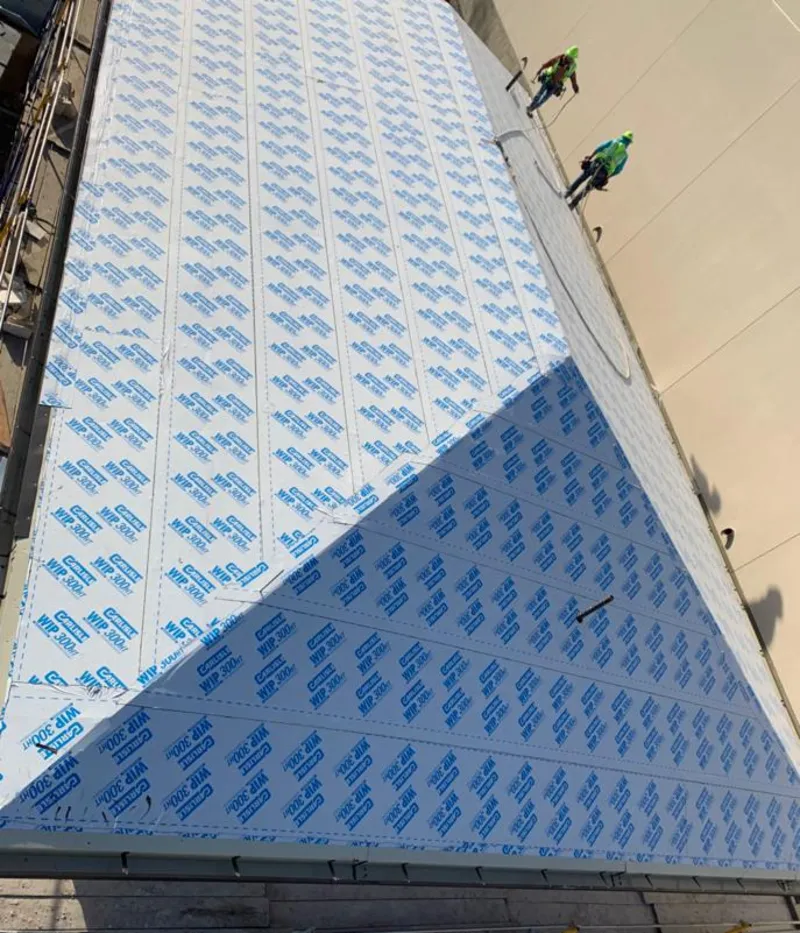 Professional roofers installing underlayment on a metal roof in Henniker